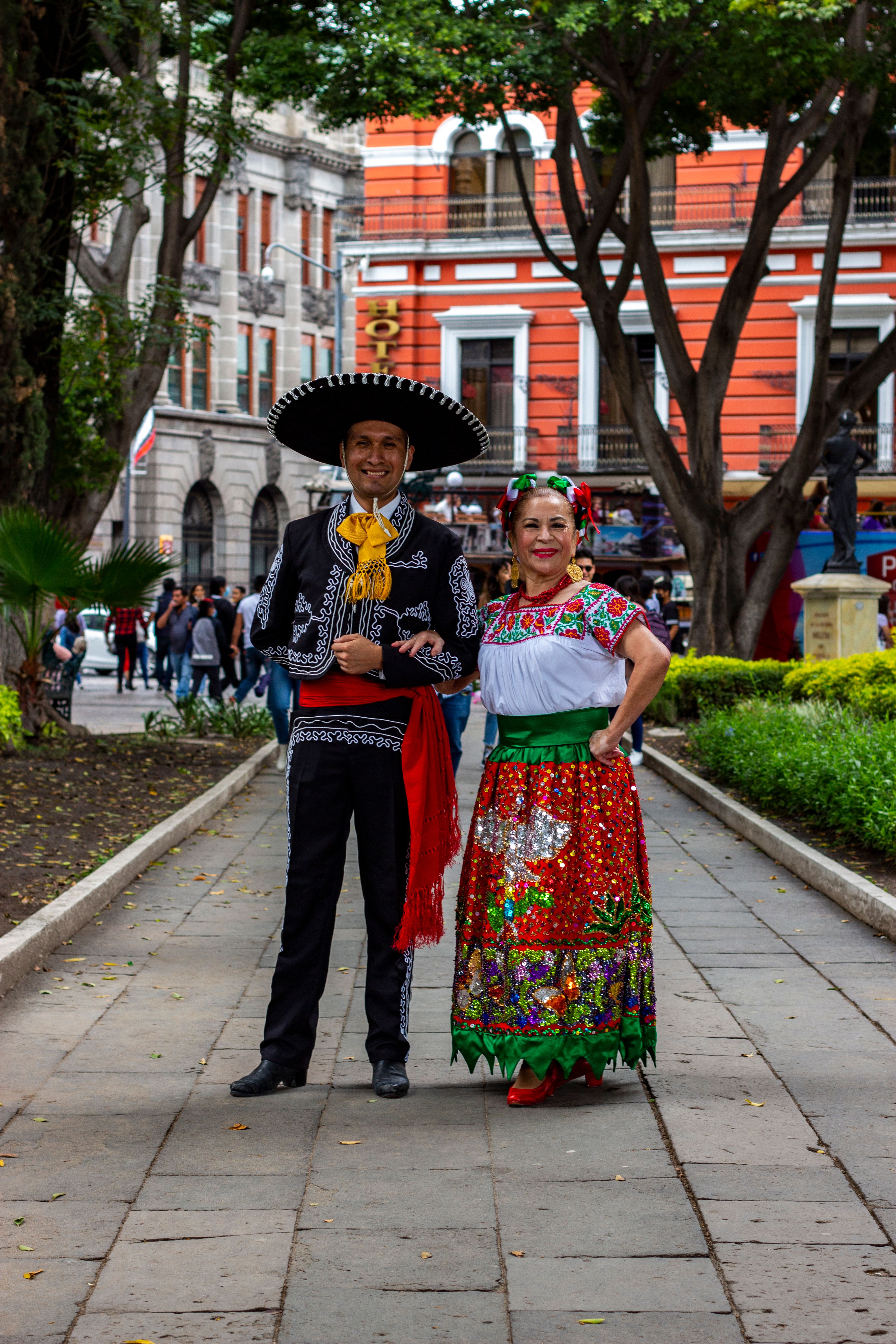 A couple in traditional Mexican charro and China Poblana dress in a city plaza