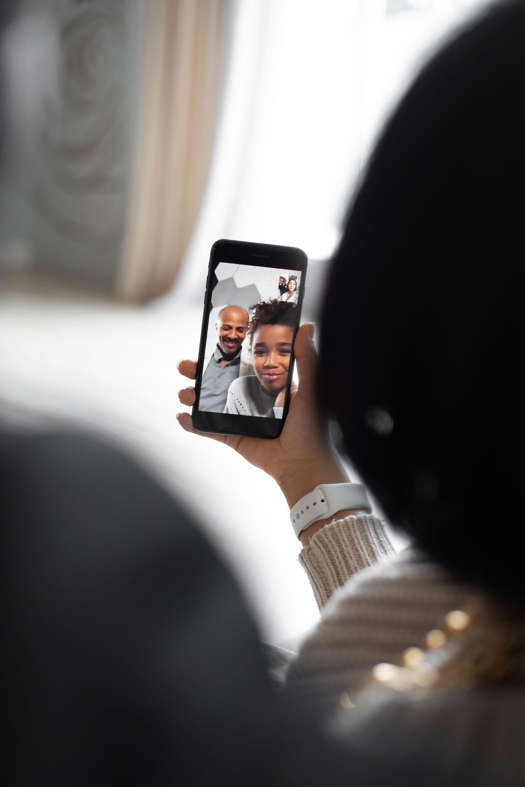 A woman on a video call with a man and a child on her phone screen