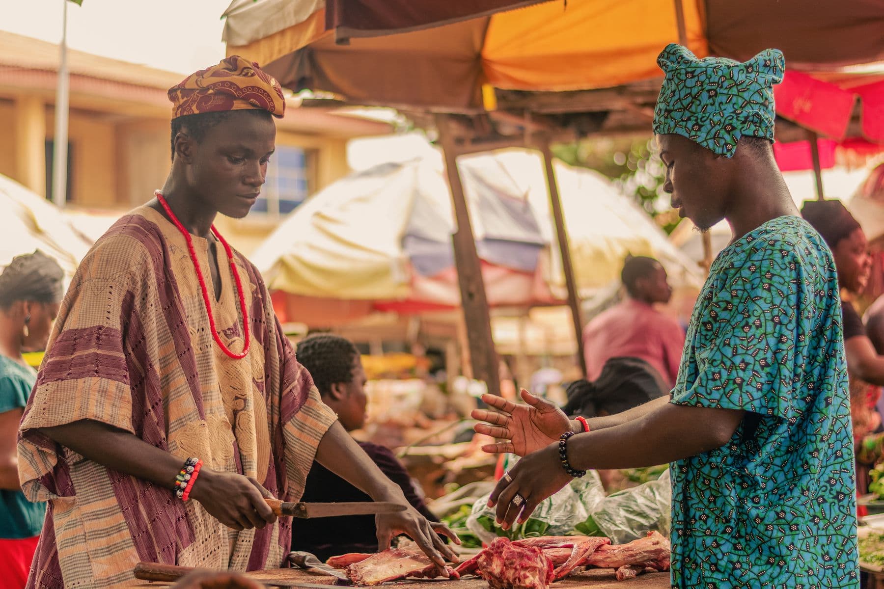 Two traders greeting each other across a busy market stall